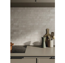 Kuchynská scéna s obkladačkami, varnou doskou a kuchynským náčiním na pracovnej doske.