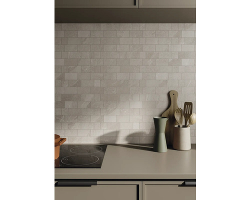 Kuchynská scéna s obkladačkami, varnou doskou a kuchynským náčiním na pracovnej doske.