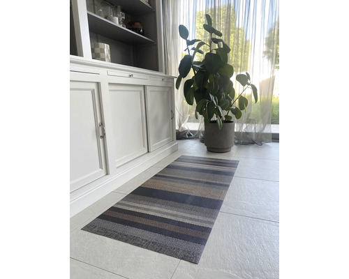 Interiérová fotografia pruhovaného koberca pred skriňou a izbovou rastlinou.