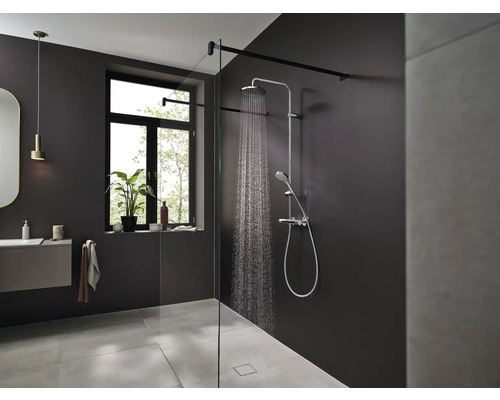 Moderná kúpeľňa so sprchou, umývadlom a oknom pre svetlé a priateľské prostredie.