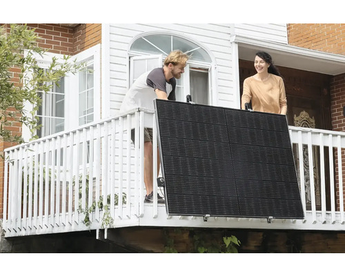 Dvaja ľudia inštalujú solárny panel na balkóne.