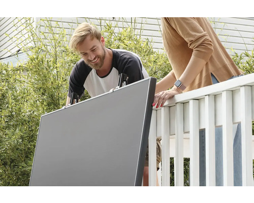 Dve osoby inštalujú pomocou svoriek plastovú zástenu na balkón.