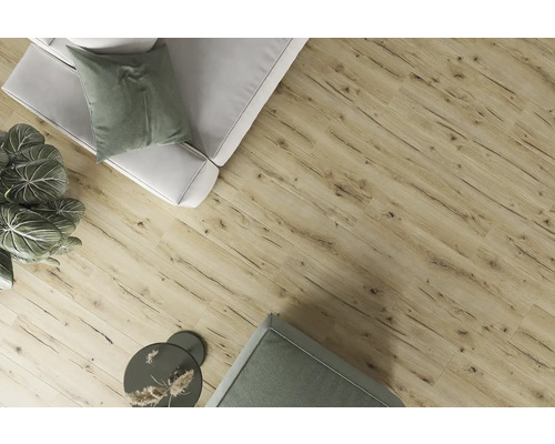 Pohľad na miestnosť s laminátovou podlahou s dreveným vzhľadom, pohovkou, ozdobnými vankúšmi, izbovou rastlinou a príručným stolíkom.