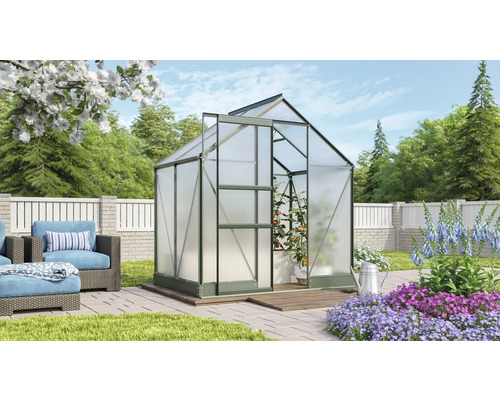 Skleník v záhrade s rastlinami a záhradným nábytkom