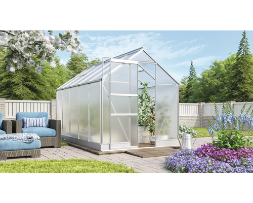 Skleník s otvorenými dverami v záhrade so záhradným nábytkom a kvetinovými záhonmi.