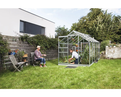 Skleník v záhrade s dvoma ženami, jedna záhradníči, druhá sedí.