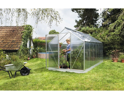 Skleník v záhrade so ženou a rastlinami