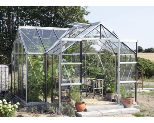 Skleník s rastlinami, stoličkou a kvetináčmi v záhrade