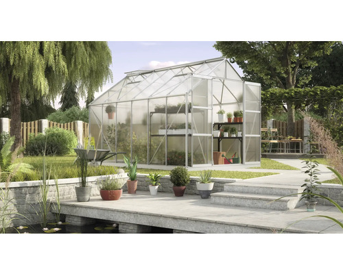 Skleník v záhrade s policami na rastliny a záhradným príslušenstvom