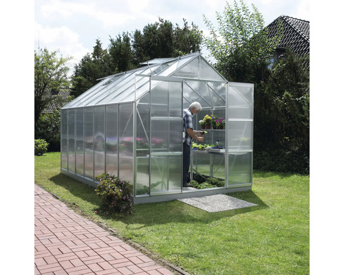 Skleník s osobou, rastlinami a policami v záhrade.