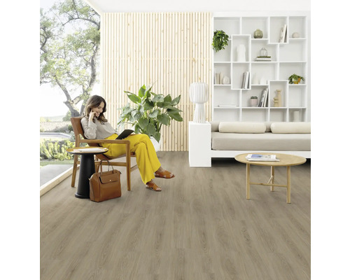 Obývacia izba s drevenou podlahou a ženou sediacou na stoličke