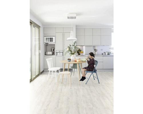 Svetlá kuchyňa s jedálenským stolom, stoličkami a dievčaťom, ktoré je.