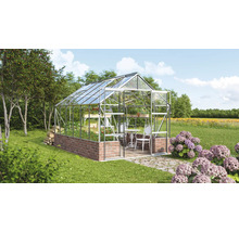 Sklenený a kamenný skleník v záhrade so stolom a stoličkami