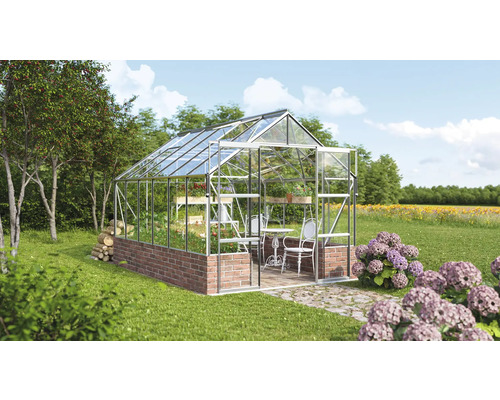 Sklenený a kamenný skleník v záhrade so stolom a stoličkami