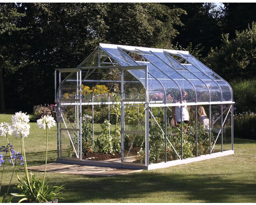 Skleník s rastlinami a záhradou v pozadí