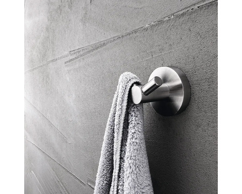 Kovový vešiak na uteráky s uterákom na sivej stene