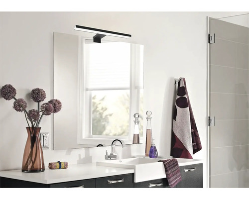 Moderná kúpeľňa s umývadlom, zrkadlom, lampou a dekoráciami.