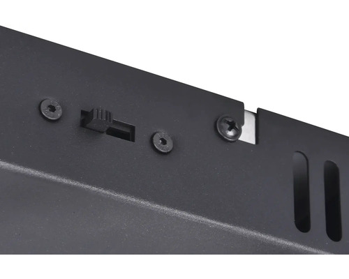 Detailný záber spínača a skrutiek na čiernej kovovej skrini.