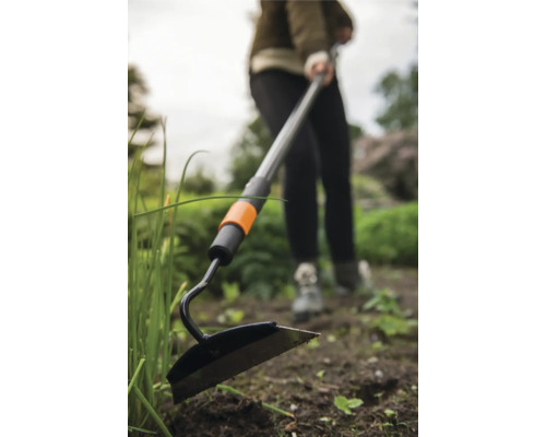 Záhradná motyka s teleskopickou násadou používaná v záhrade.