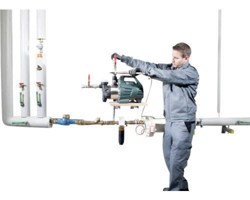 Inštalatér montuje záhradné čerpadlo na potrubný systém.