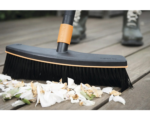 Kefa na čistenie drevenej terasy so zvyškami rastlín.