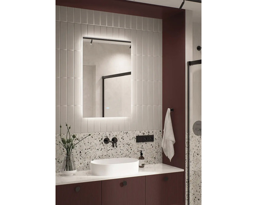 Moderná kúpeľňa s osvetleným zrkadlom, umývadlom na dosku a akcentovou stenou z terazza.