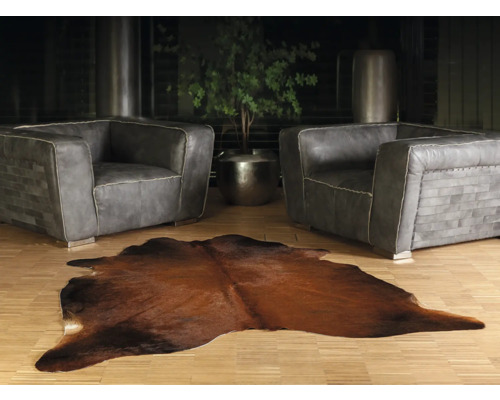 Obývacia izba s dvoma sivými koženými kreslami a hnedým kobercom z kravskej kože