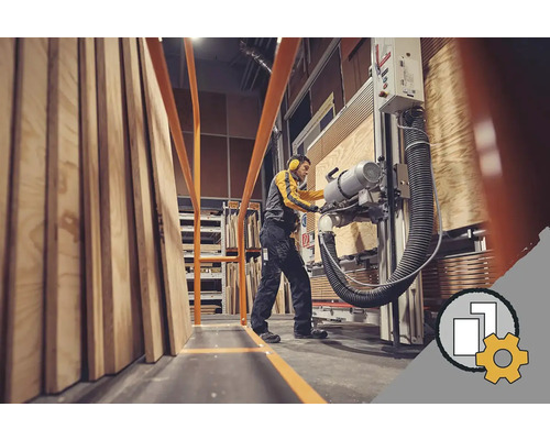 Zamestnanec reže drevené dosky na formátovacej píle v sklade.