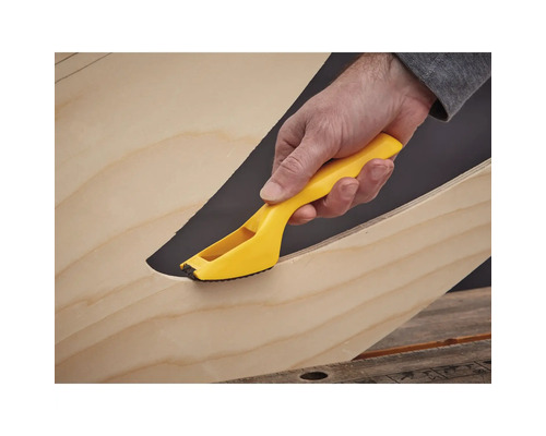 Ruka so žltým odhrotovacím nástrojom na hrane dreva