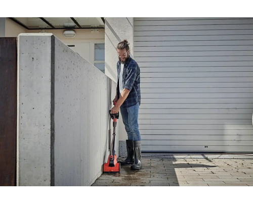 Muž čistí betónovú stenu elektrickou kefou vonku