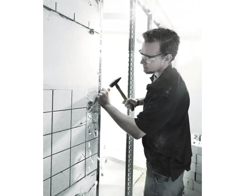 Remeselník odstraňuje dlaždice pomocou kladiva a dláta