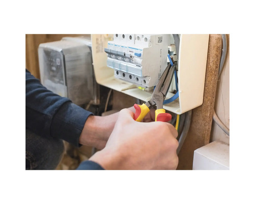 Elektrikár pracuje s kombinovanými kliešťami na rozvodnej skrini