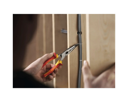 Osoba pripevňuje drôt na stenu pomocou klieští