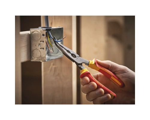 Ruka drží zahnuté kliešte s dlhými čeľusťami značky Stanley na prácu s káblami v rozvodnej krabici.