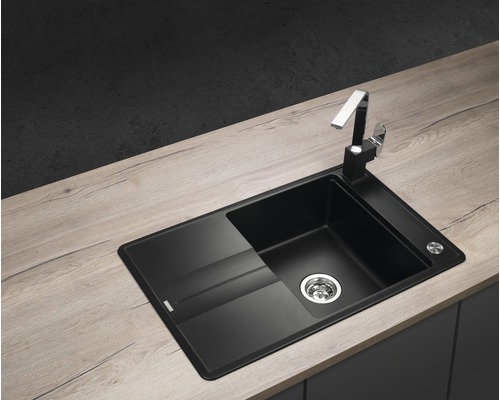 Čierny kuchynský drez s odkvapkávacou plochou a vodovodnou batériou na pracovnej doske