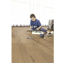 Dieťa maľuje na drevenej podlahe. V pozadí je plyšový slon.