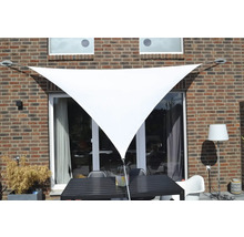 Trojuholníková slnečná plachta nad terasovým stolom so stoličkami pri stene domu