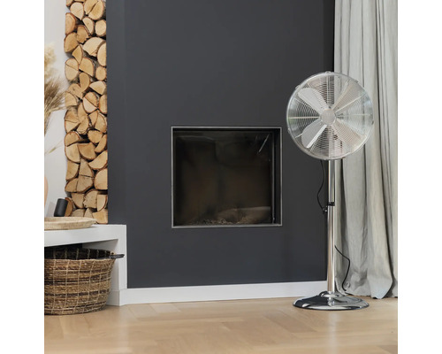Obývacia izba s krbom, palivovým drevom a stojacim ventilátorom