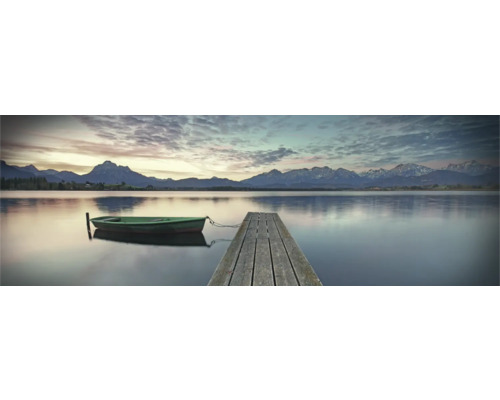 Kojné jazero s dreveným mólom a malou loďou v popredí, s horskou krajinou v pozadí.