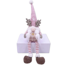 Dekoratívny vianočný škriatok s čiapkou, parožím a pruhovanými nohami sedí na bielom povrchu