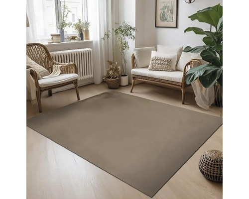 Obývacia izba s kobercom, ratanovým kreslom a pohovkou vo svetlom dizajne.