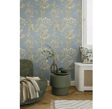 Dekoratívna obývacia izba s kvetinovou tapetou, kreslom a príručným stolíkom.