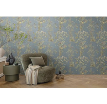 Zdobená izba s kvetinovou tapetou, kreslom a príručným stolíkom.