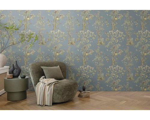 Zdobená izba s kvetinovou tapetou, kreslom a príručným stolíkom.