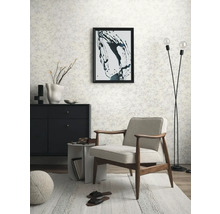 Obývacia izba s kreslom, komodou, stojacou lampou a vzorovanou tapetou pre svetlú a usporiadanú atmosféru