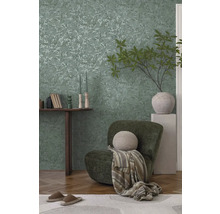 Dekoratívny obývací priestor s tapetou s motívom listov, kreslom a dreveným stolom