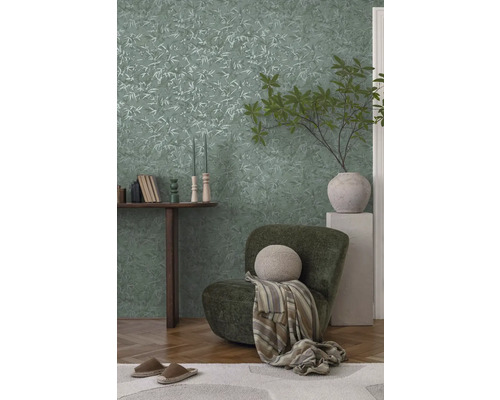 Dekoratívny obývací priestor s tapetou s motívom listov, kreslom a dreveným stolom