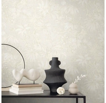 Scéna s béžovou tapetou s rastlinným vzorom, stôl s dekoráciami ako sú sochy a vázy