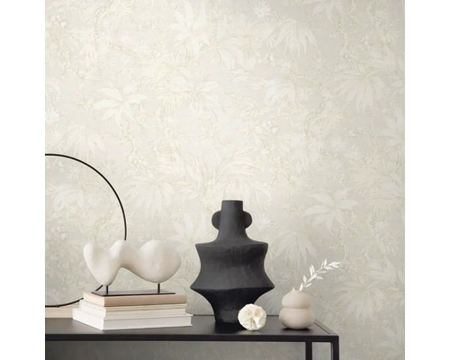 Scéna s béžovou tapetou s rastlinným vzorom, stôl s dekoráciami ako sú sochy a vázy