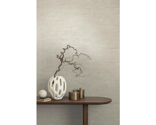 Dekoratívna váza s vetvou na drevenom stole pred štruktúrovanou stenou